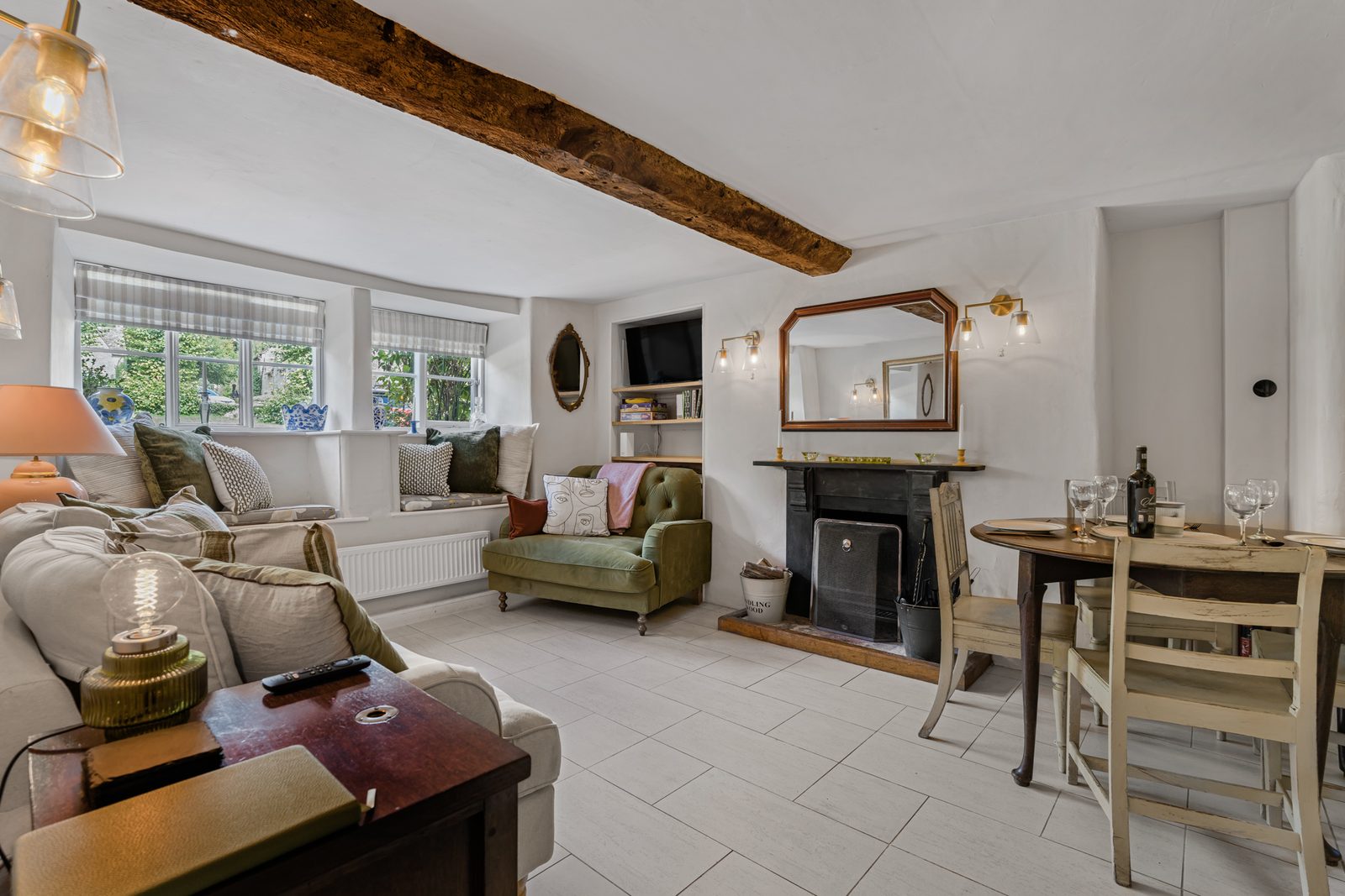 Living room at Green Hideaway with open fire, window seats and cream sofas