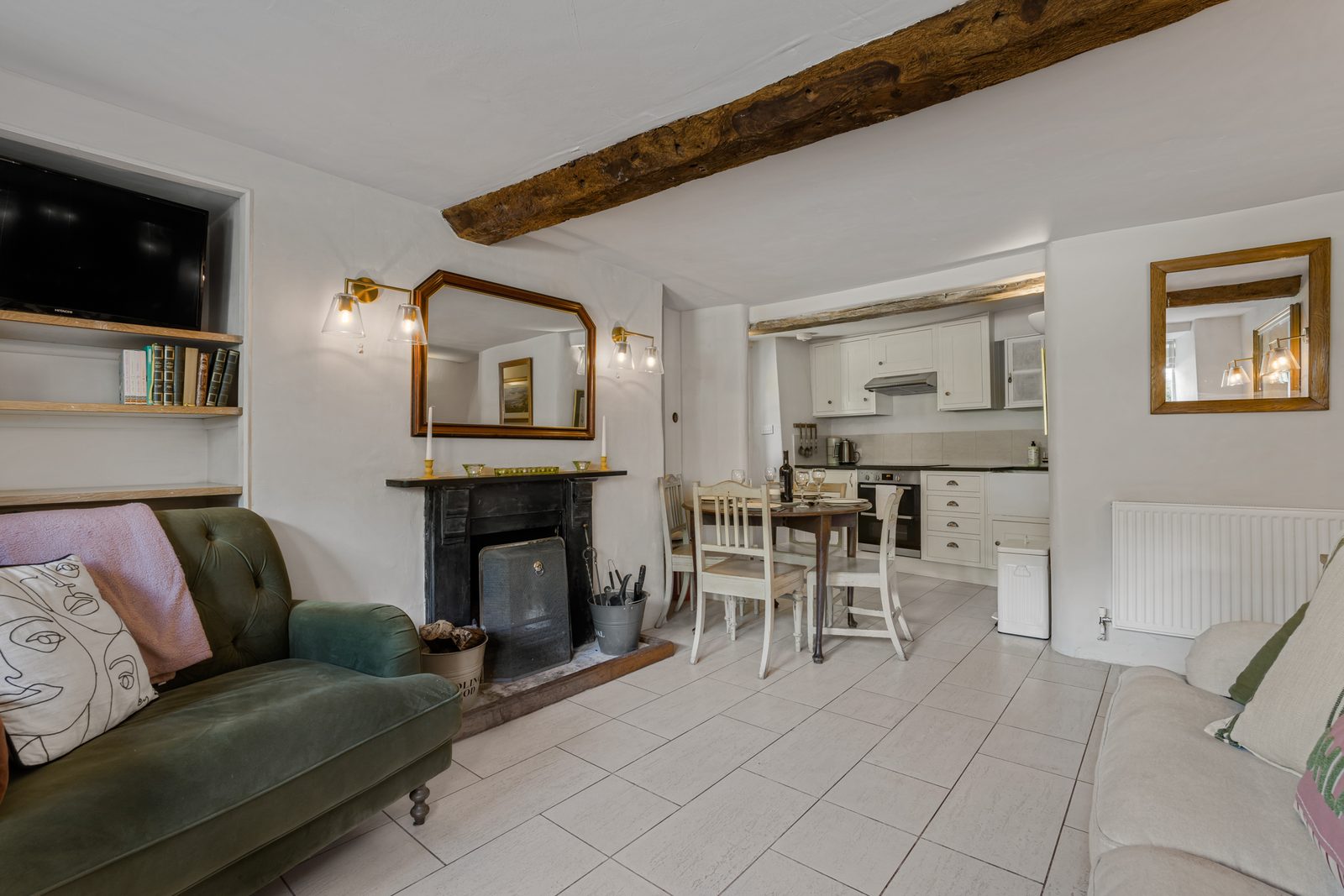 Green velvet sofa and open fire in the living room at Green Hideaway