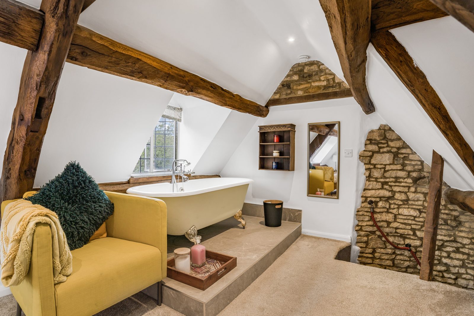 Roll-top bath and yellow sofa under the beams at Riverside Cottage