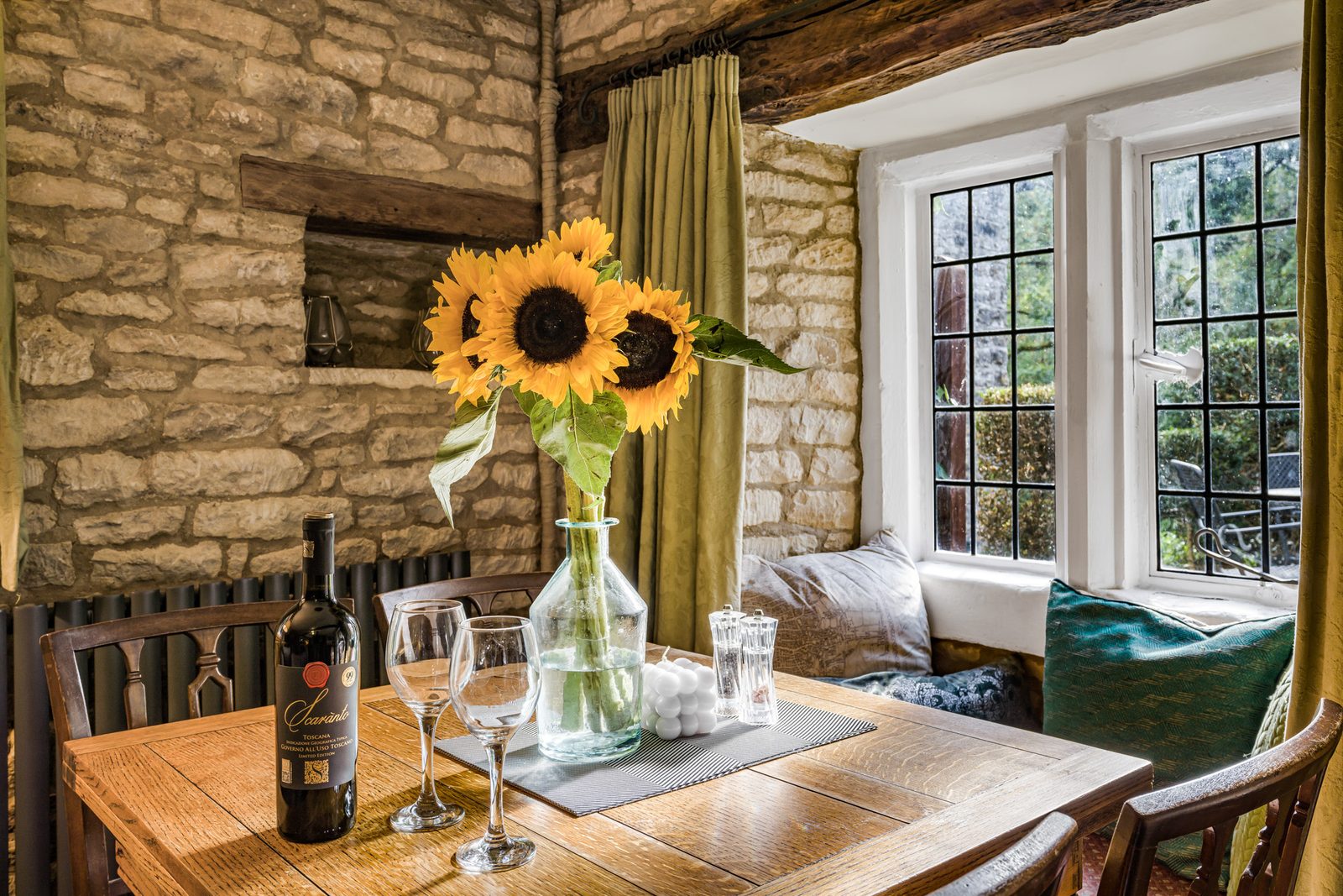 Dining table at Riverside Cottage with sunflowers and the window seat behind