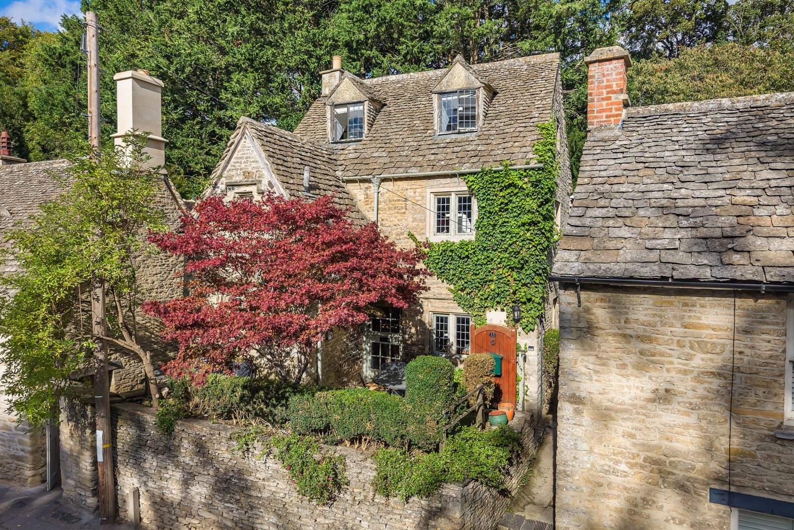 Riverside Cottage and its stone roofs seen from above with the red acer in leaf