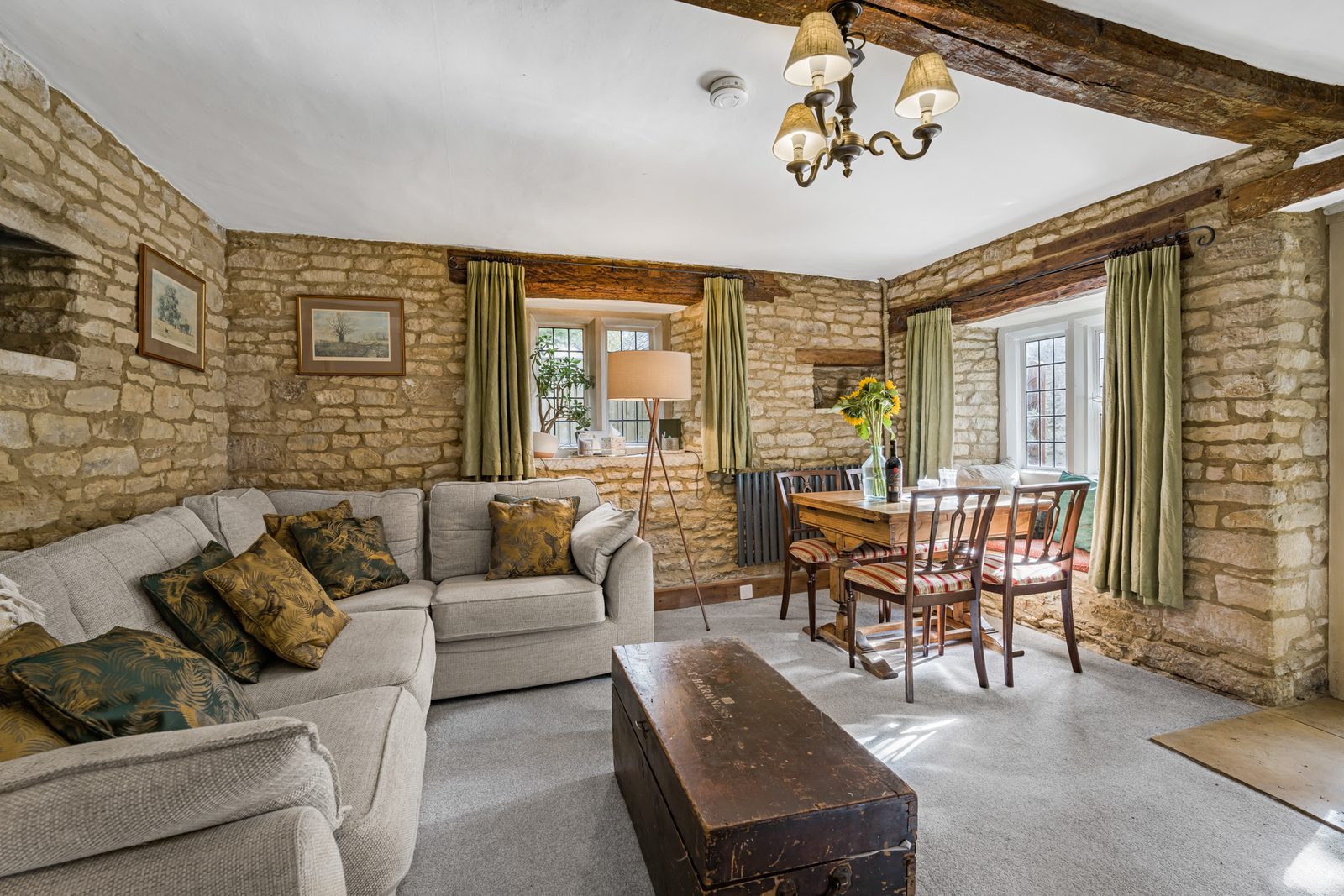 Living room at Riverside Cottage with exposed Cotswold stone wall and sofa under the beam