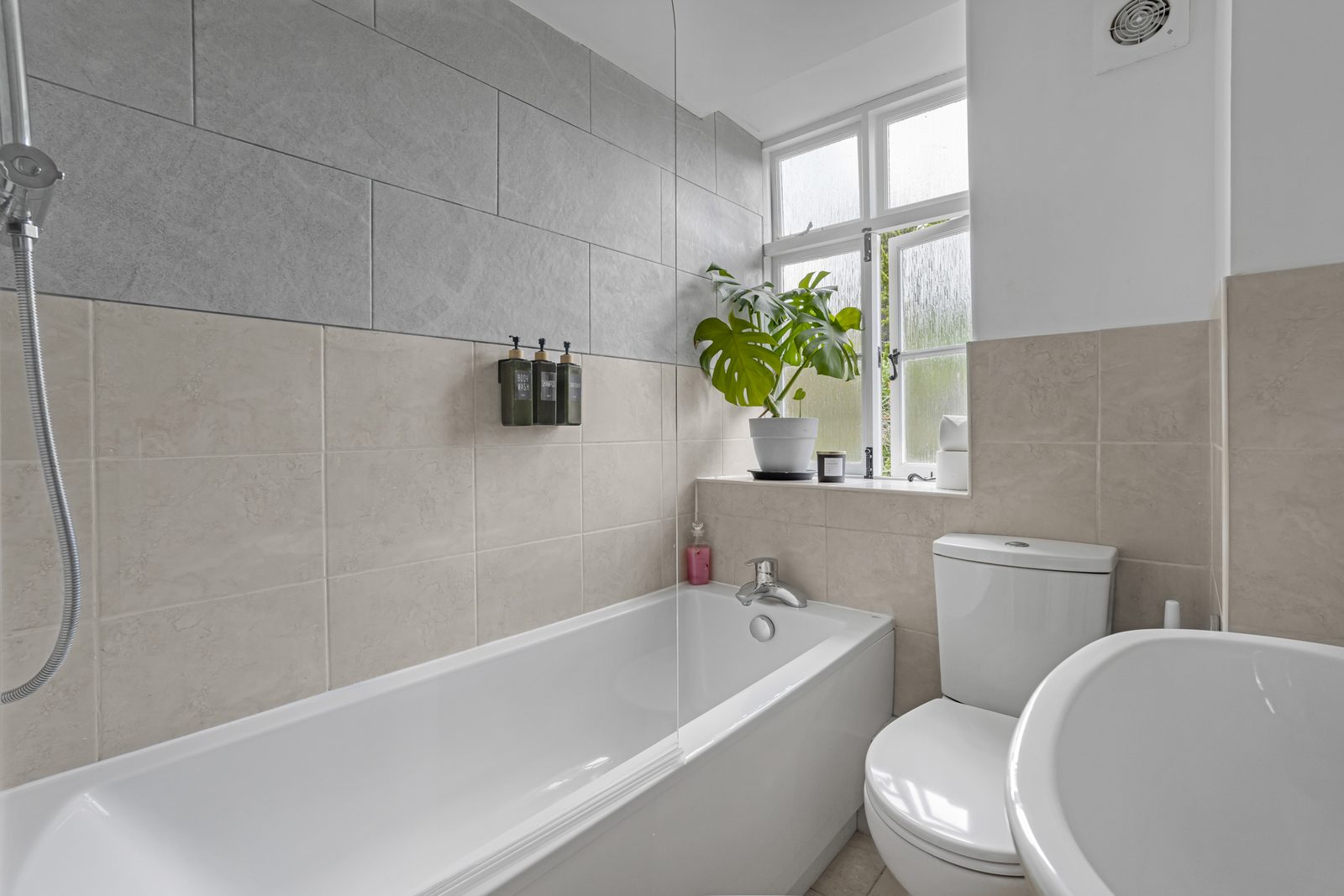 Bathroom at Rosemary Cottage with bath, stone tiling and a plant on the sill