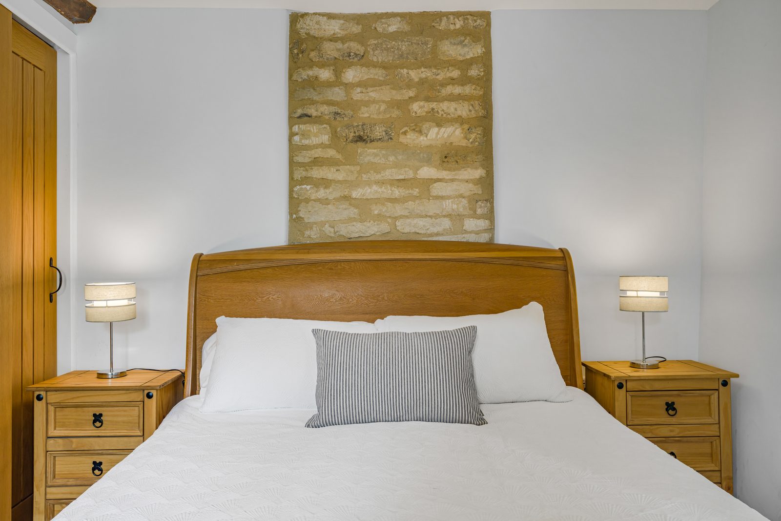 Oak sleigh bed against the exposed stone chimney breast at Rosemary Cottage