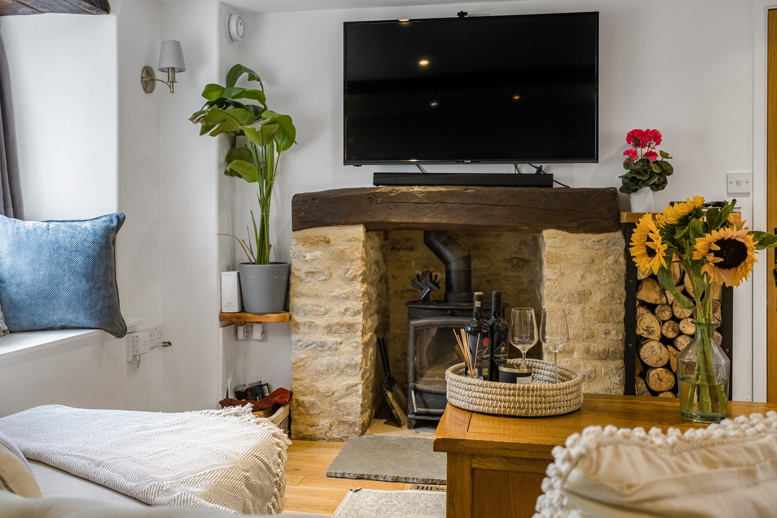 Inglenook fireplace with woodburner and stacked logs in the living room at Rosemary Cottage